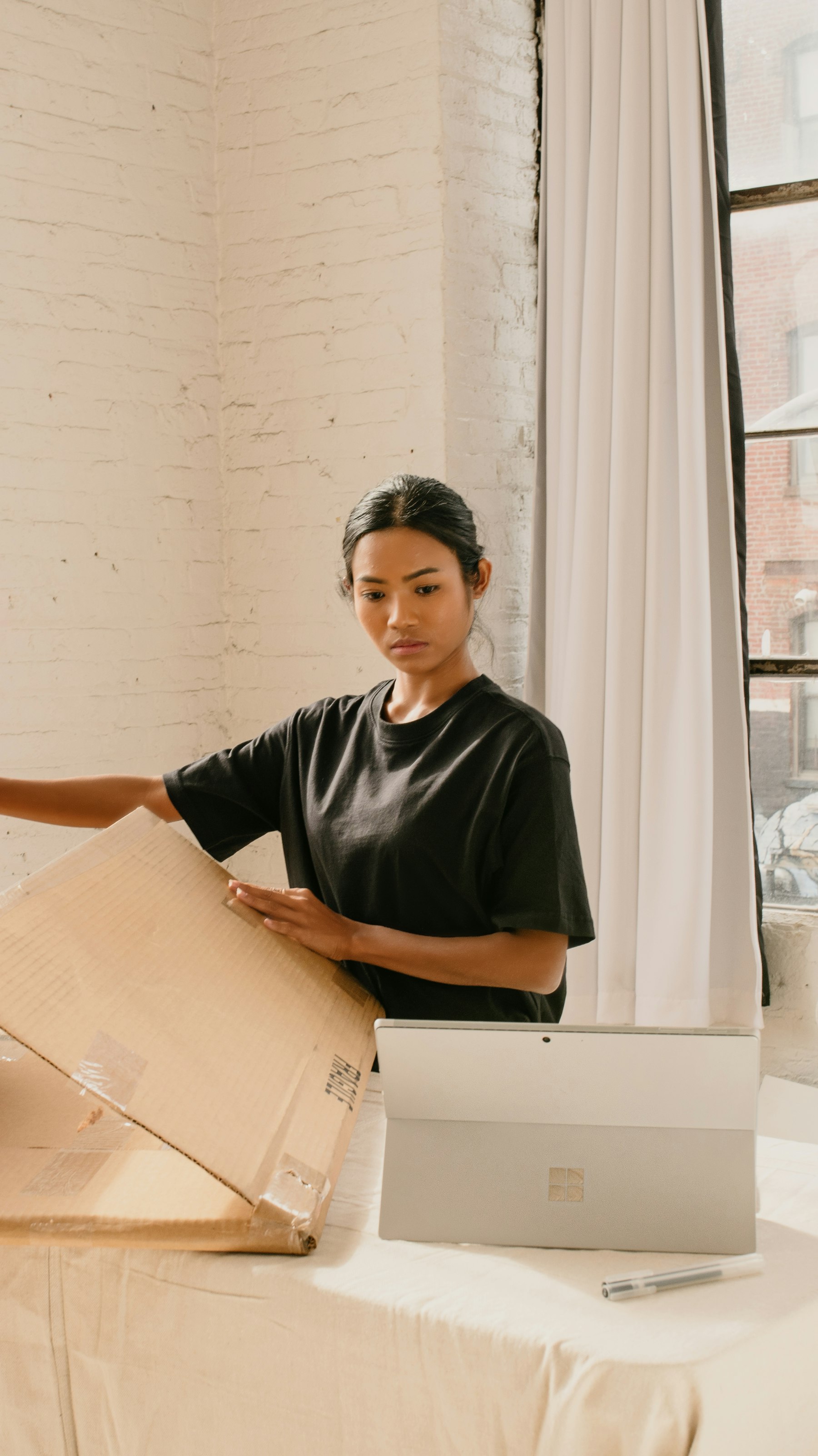 An online store owner packing a customer order into a shipping box at her desk